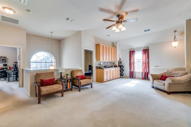 sitting room with a ceiling fan, light colored carpet, and visible vents