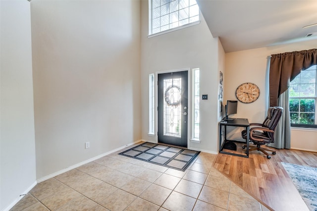 entryway with baseboards, a towering ceiling, and light tile patterned floors