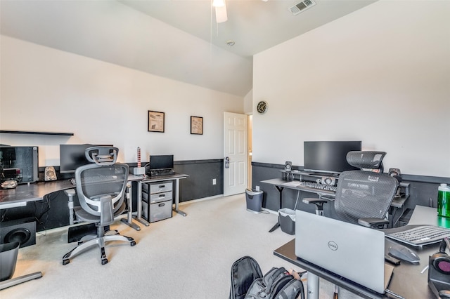 office area featuring carpet flooring, a wainscoted wall, a ceiling fan, vaulted ceiling, and visible vents