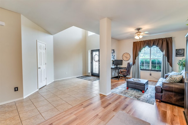 living room with baseboards, a ceiling fan, and light wood-style flooring