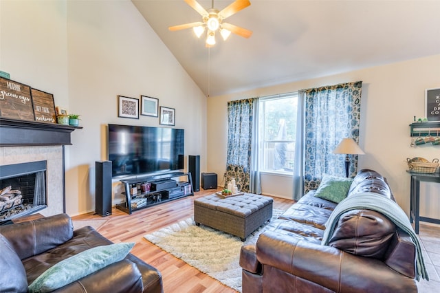 living room with high vaulted ceiling, a tile fireplace, ceiling fan, and wood finished floors