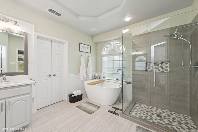 13283 Bodega Trl, Frisco, TX 75035 - bathroom featuring visible vents, vanity, wainscoting, a soaking tub, and a shower stall