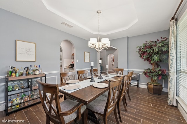 13283 Bodega Trl, Frisco, TX 75035 - dining space with visible vents, an inviting chandelier, wood tiled floor, a raised ceiling, and arched walkways