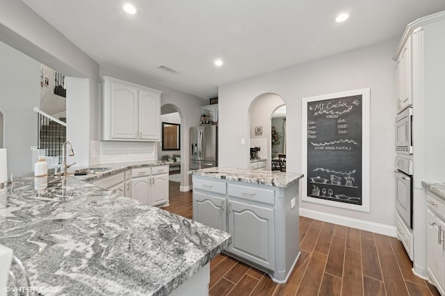 13283 Bodega Trl, Frisco, TX 75035 - kitchen with arched walkways, appliances with stainless steel finishes, a sink, dark wood-style floors, and recessed lighting