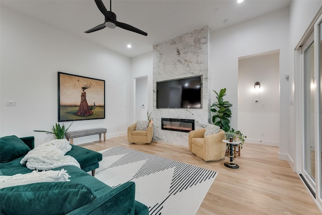 living room with recessed lighting, light wood finished floors, ceiling fan, and a premium fireplace