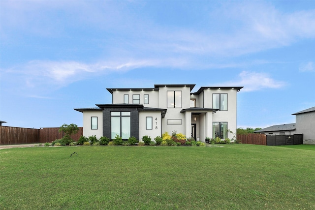 view of front of home featuring stucco siding, fence, and a front lawn