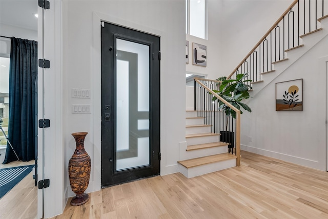 entryway featuring baseboards, stairs, and wood finished floors
