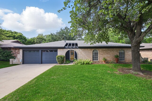 single story home featuring driveway, a garage, brick siding, and a front lawn