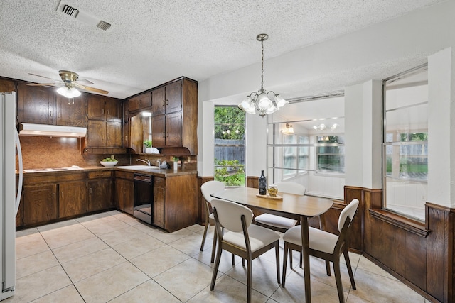 kitchen featuring under cabinet range hood, white refrigerator, a textured ceiling, dishwasher, and light tile patterned floors