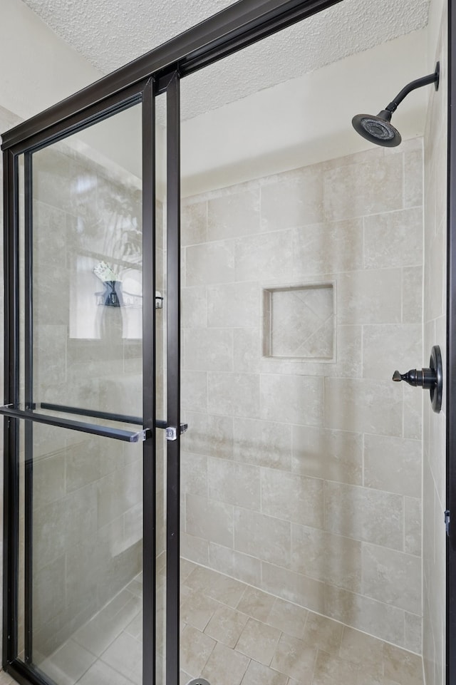 bathroom with a shower stall and a textured ceiling