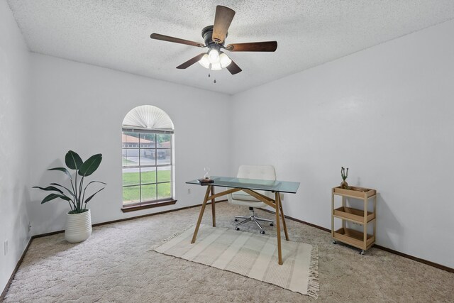 carpeted home office with a textured ceiling, a ceiling fan, and baseboards