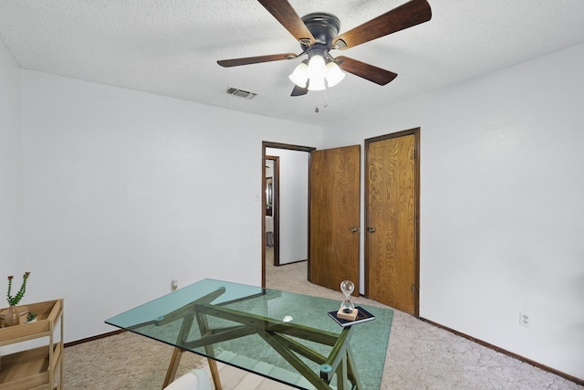 office area with light colored carpet, a ceiling fan, baseboards, and a textured ceiling