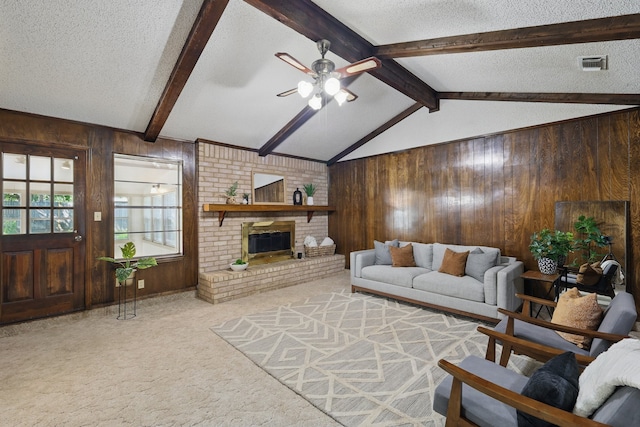 carpeted living area with a ceiling fan, wood walls, a fireplace, and a textured ceiling