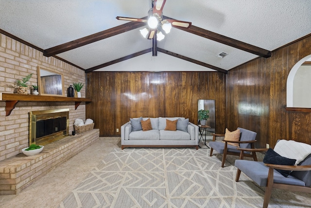 living area featuring light colored carpet, a textured ceiling, ceiling fan, wood walls, and a fireplace