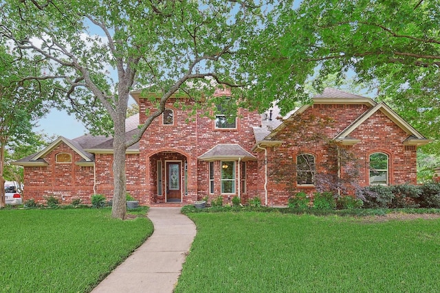 traditional home featuring a front lawn, brick siding, and a shingled roof