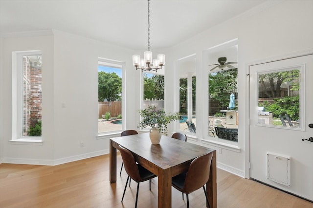dining area with light wood-type flooring, a chandelier, ceiling fan, crown molding, and baseboards