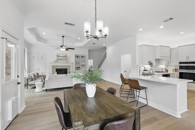 dining room with ceiling fan, light wood finished floors, recessed lighting, ornamental molding, and a glass covered fireplace