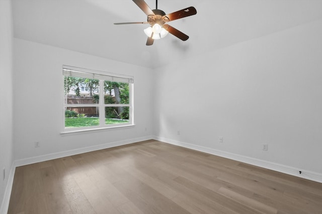 empty room with wood finished floors, baseboards, and a ceiling fan