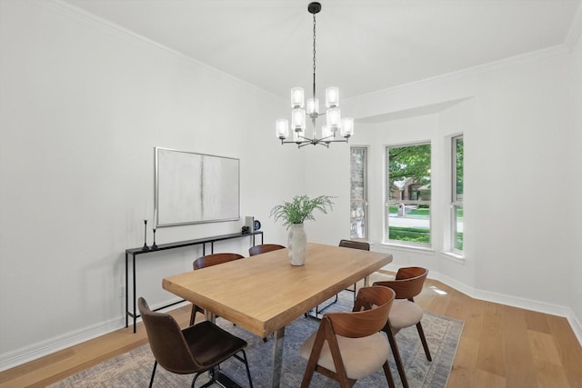 dining room with crown molding, light wood-style floors, a chandelier, and baseboards