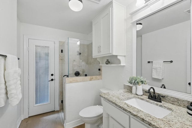 full bathroom featuring a shower stall, vanity, toilet, and wood finished floors