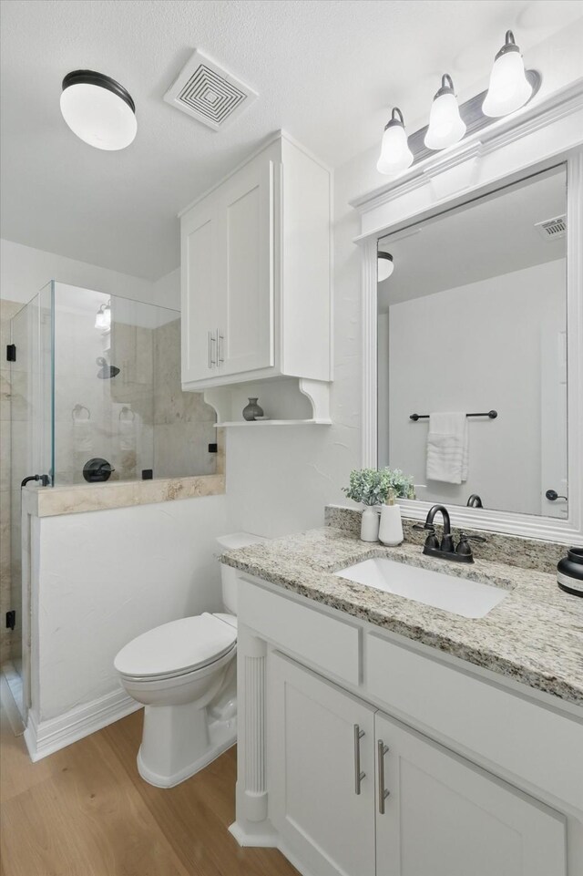 full bath featuring wood finished floors, a stall shower, toilet, and vanity