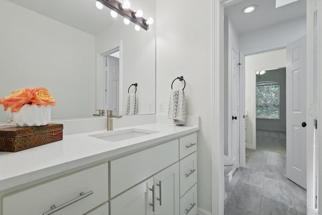 bathroom featuring marble finish floors, vanity, baseboards, and recessed lighting
