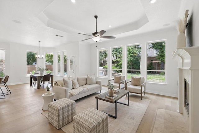 living area featuring a tray ceiling, light wood-type flooring, healthy amount of natural light, and recessed lighting