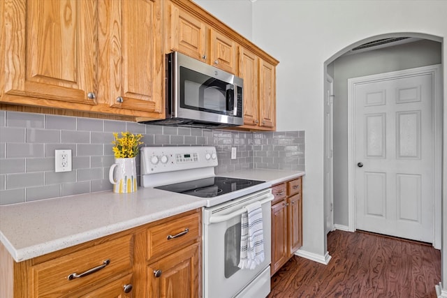 817 Countryside Dr, Aubrey, TX 76227 - kitchen with stainless steel microwave, white electric stove, arched walkways, dark wood-style flooring, and decorative backsplash
