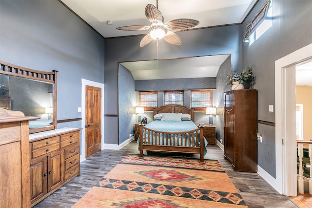 bedroom featuring a towering ceiling, baseboards, a ceiling fan, and wood finished floors