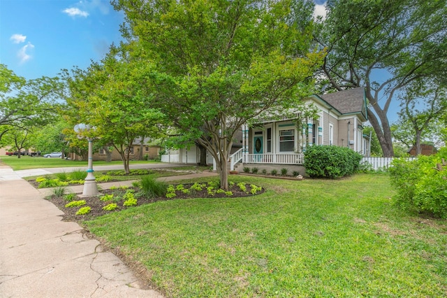 view of property hidden behind natural elements featuring a porch, a garage, driveway, and a front yard