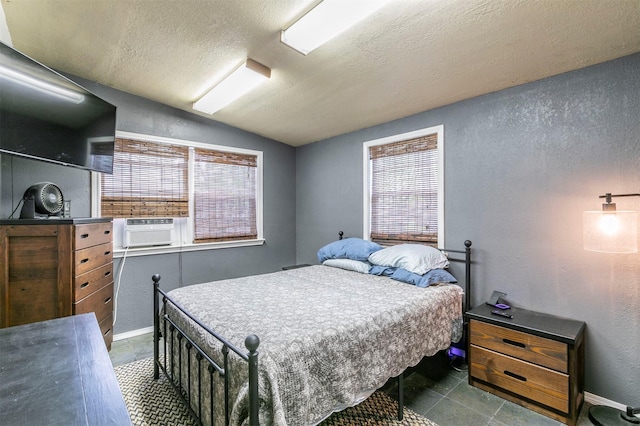 bedroom with dark tile patterned floors, a textured wall, a textured ceiling, and lofted ceiling