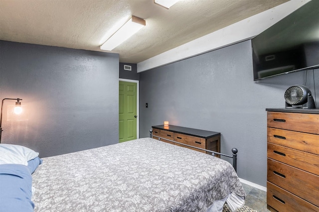bedroom featuring a textured ceiling, visible vents, a textured wall, and baseboards