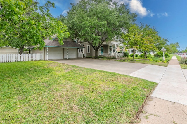 view of front of property featuring an attached garage, fence, driveway, and a front yard