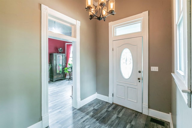 entrance foyer with baseboards, a notable chandelier, visible vents, and wood finished floors