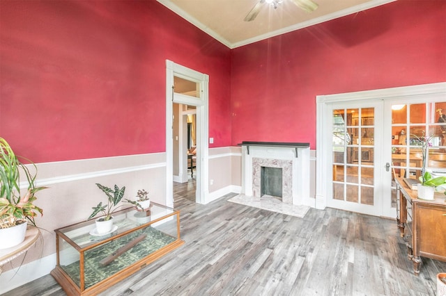 living room with crown molding, a fireplace, french doors, a ceiling fan, and wood finished floors