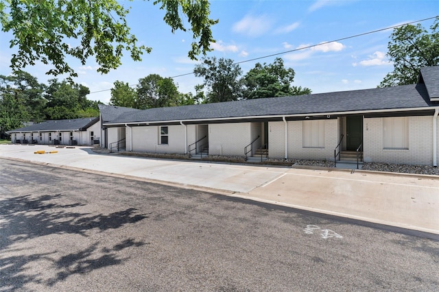ranch-style home featuring entry steps, roof with shingles, and brick siding