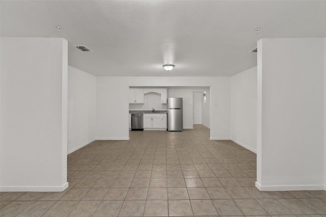 unfurnished living room featuring a sink, baseboards, and visible vents