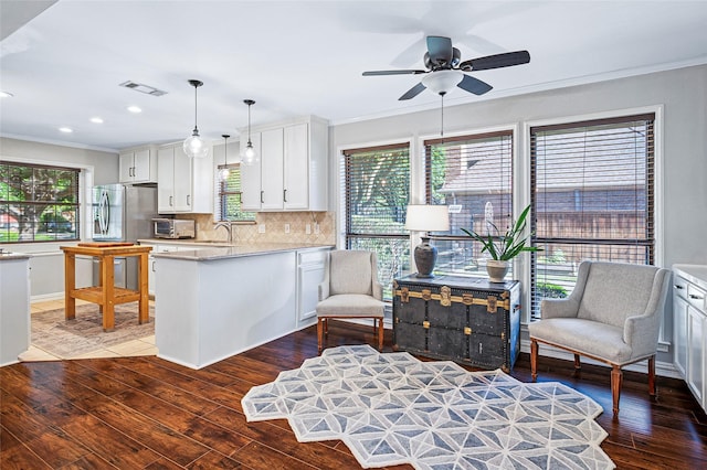 kitchen featuring crown molding, a sink, light countertops, healthy amount of natural light, and wood finished floors