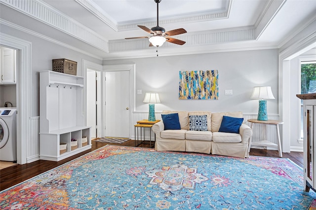 living room featuring washer / dryer, a tray ceiling, wood finished floors, ceiling fan, and ornamental molding