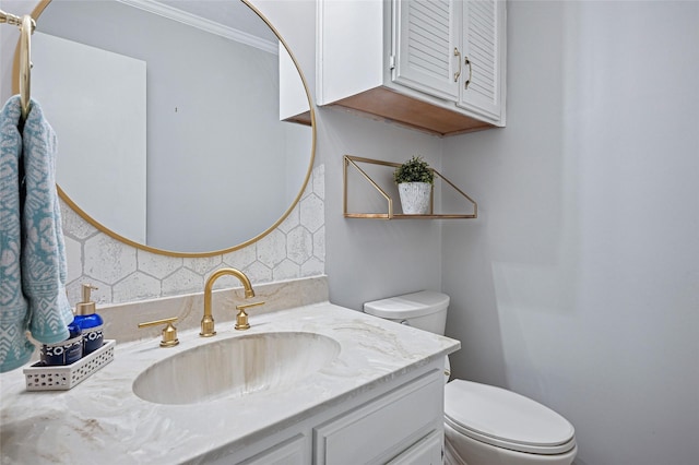 bathroom with toilet, vanity, and crown molding