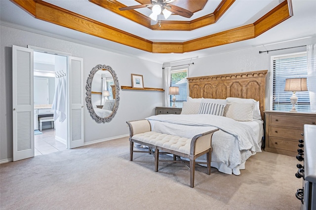 bedroom with carpet floors, a tray ceiling, ornamental molding, baseboards, and connected bathroom