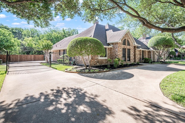 view of home's exterior with brick siding, a gate, driveway, roof with shingles, and fence