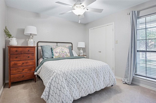 carpeted bedroom featuring baseboards, a closet, and a ceiling fan