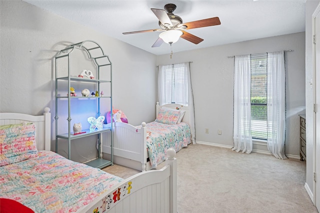 carpeted bedroom featuring multiple windows, a ceiling fan, and baseboards