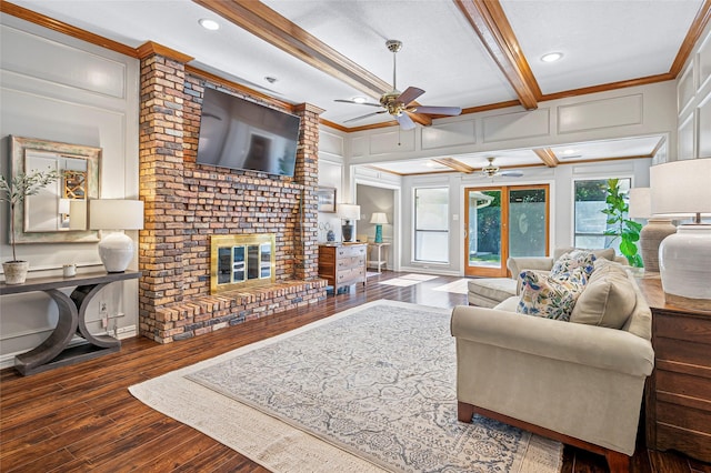 living room with a decorative wall, ceiling fan, wood finished floors, ornamental molding, and a fireplace