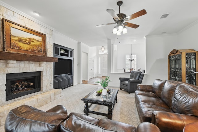 living room with a stone fireplace, visible vents, crown molding, built in shelves, and ceiling fan with notable chandelier