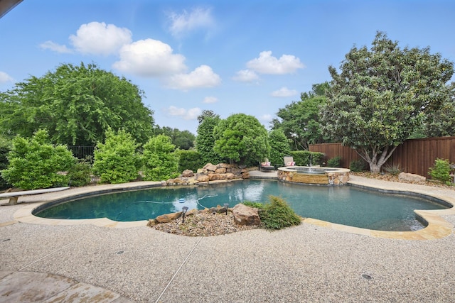 view of swimming pool with a diving board, a pool with connected hot tub, fence, and a patio area