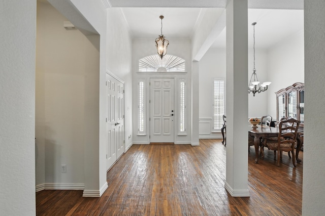 entryway with dark wood-type flooring, baseboards, a towering ceiling, and a notable chandelier