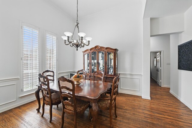 dining area featuring a high ceiling, ornamental molding, dark wood-style flooring, and a chandelier