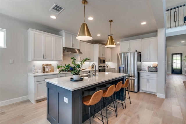 kitchen with appliances with stainless steel finishes, white cabinetry, tasteful backsplash, under cabinet range hood, and visible vents